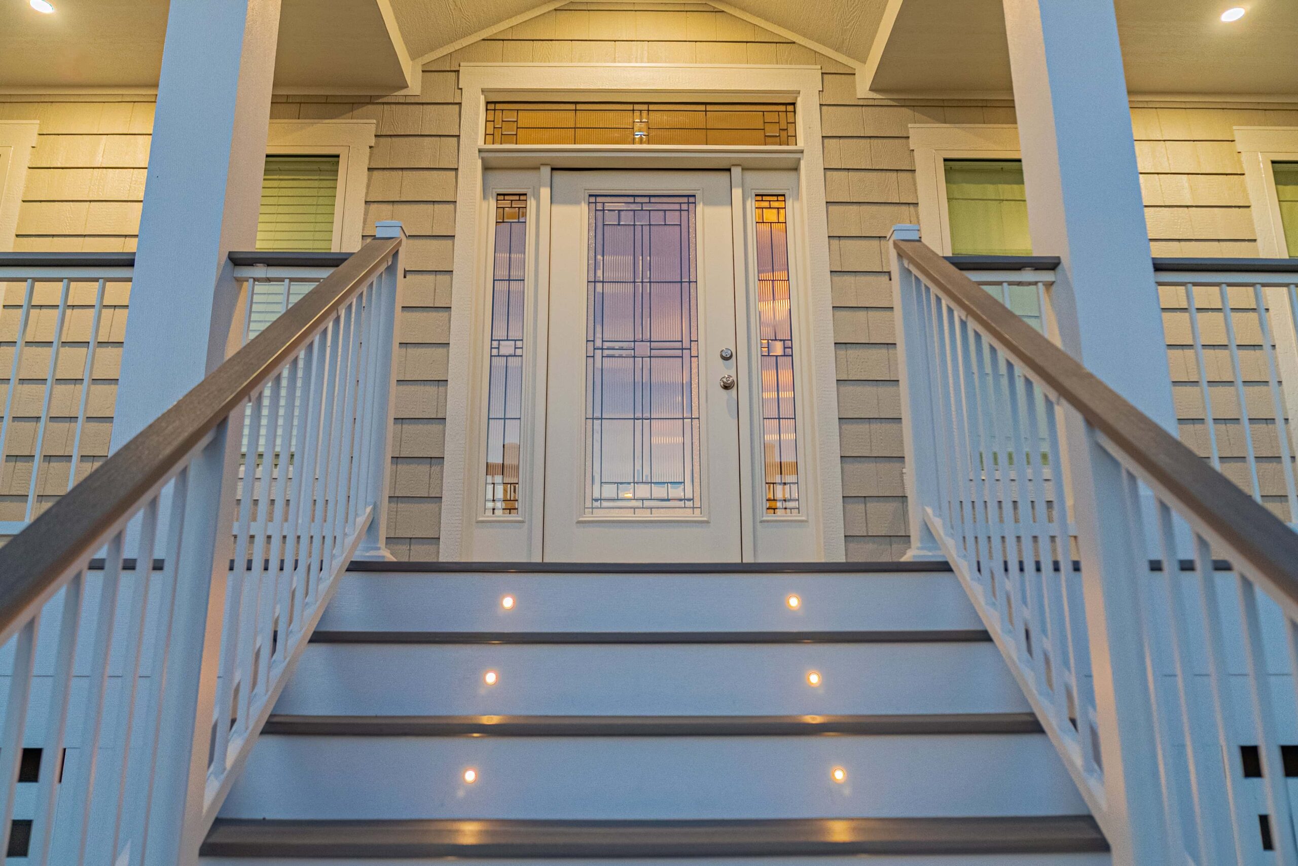 deck-stairs-lighting-on-front-porch-staircase-in-white-house-with-multiple-windows-in-outer-banks-nc
