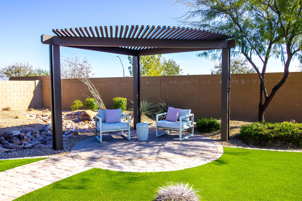 freestanding-black-pergola-covering-two-chairs-with-small-table-featuring-brick-wall-fence-in-outer-banks-nc