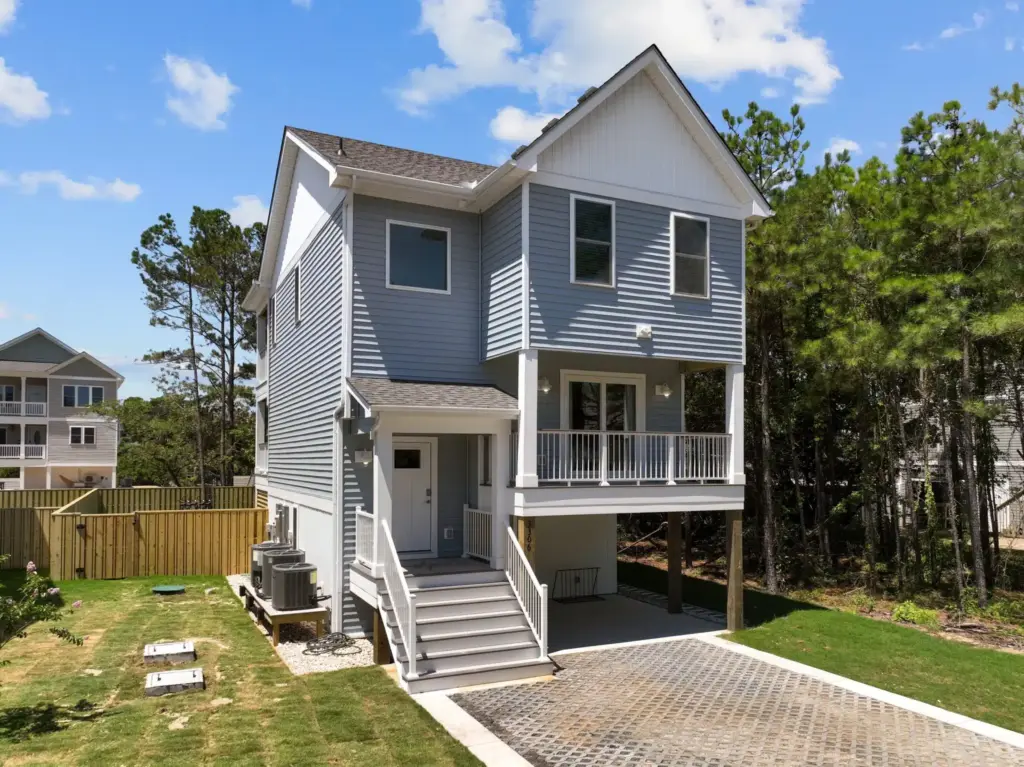 gray-house-with-raised-deck-with-white-railings-and-siding-featuring-wooden-wall-fence-in-outer-banks-nc