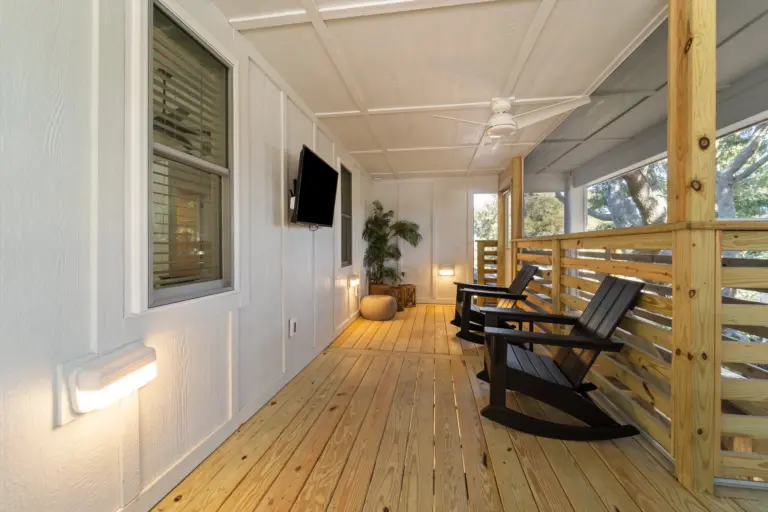 interior-of-the-screened-in-porch-with-two-black-rocking-chairs-and-a-tv-on-the-wall-in-outer-banks-nc