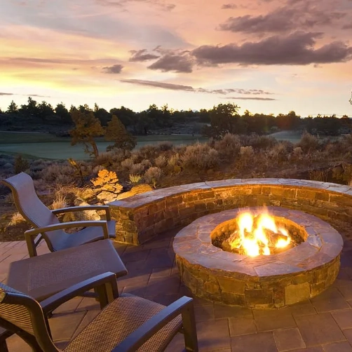 outdoor-living-fire-place-and-fire-pit-surrounded-by-grass-plants-and-trees-featuring-sunset-view-in-outer-banks-nc