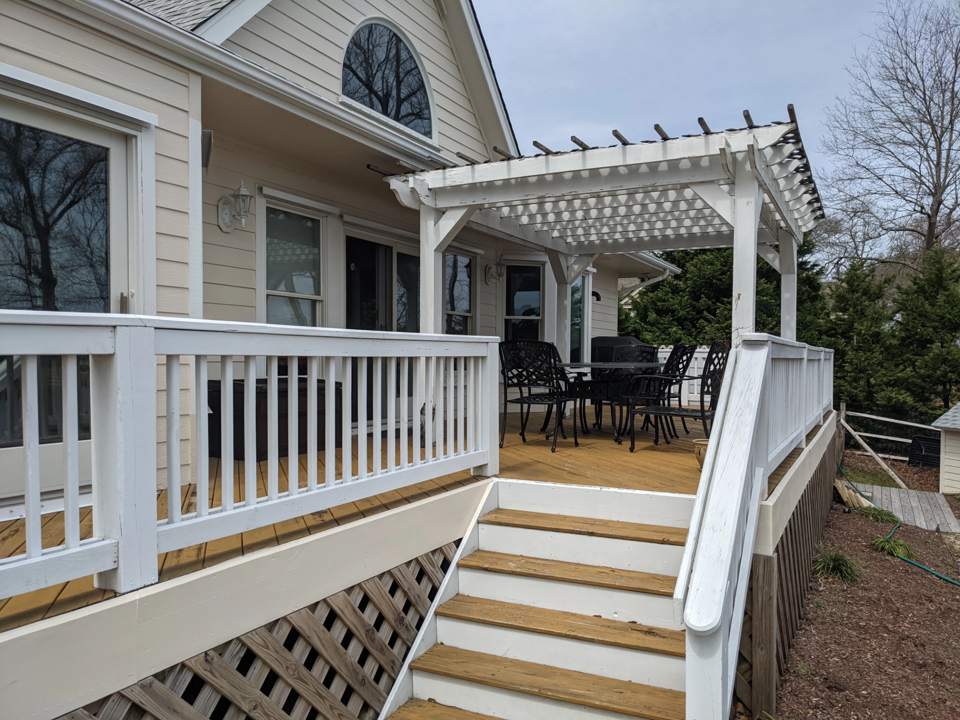 raised-deck-with-pergola-and-skiriting-on-the-deck-with-white-railings-and-outdoor-living-area-on-the-mocha-house-with-multiple-windows-in-outer-banks-nc