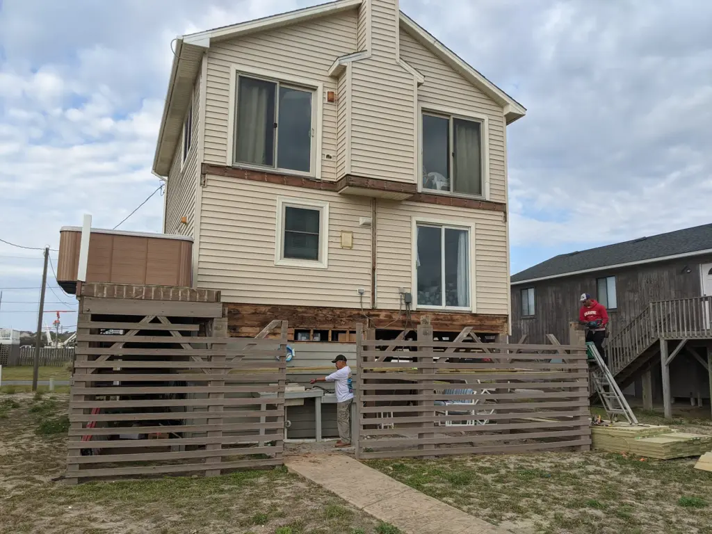 wooden-privacy-fence-construction-by-simple-side-construction-on-the-mocha-house-with-multiple-sliding-glass-windows-in-outer-banks-nc